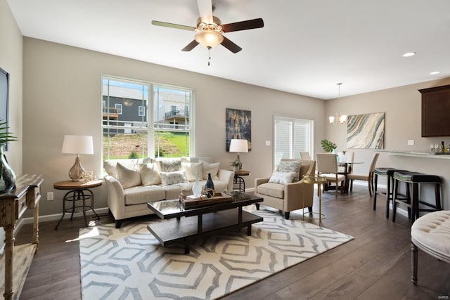 living room with ceiling fan with notable chandelier and dark hardwood / wood-style flooring