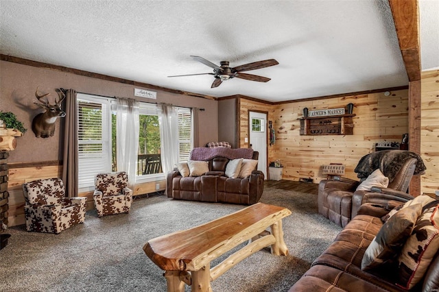 living room with ceiling fan, a textured ceiling, wooden walls, and carpet