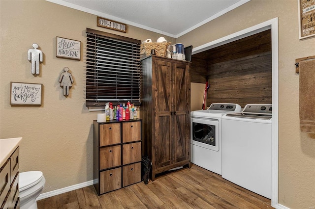 laundry area featuring light hardwood / wood-style floors, crown molding, and separate washer and dryer