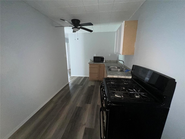 kitchen with dark wood-type flooring, sink, black gas range oven, ceiling fan, and light brown cabinetry