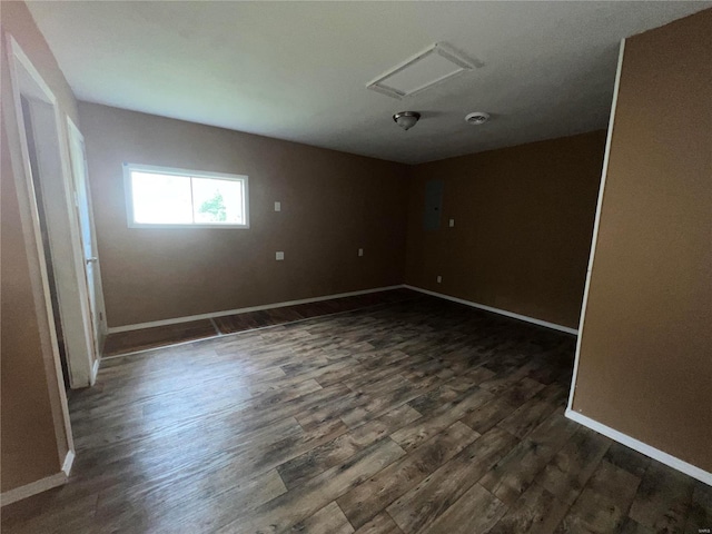 empty room with dark hardwood / wood-style floors and electric panel