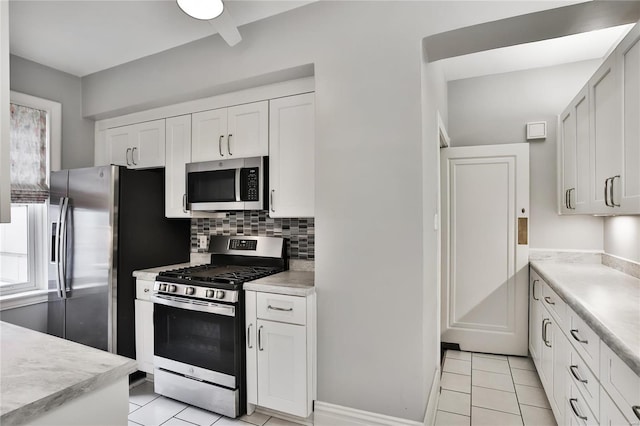 kitchen featuring appliances with stainless steel finishes, light tile patterned floors, white cabinetry, and backsplash