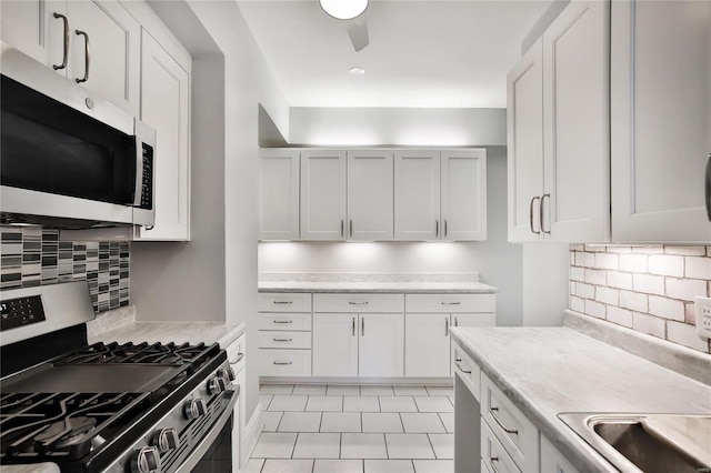 kitchen with ceiling fan, tasteful backsplash, light tile patterned flooring, white cabinetry, and stainless steel appliances