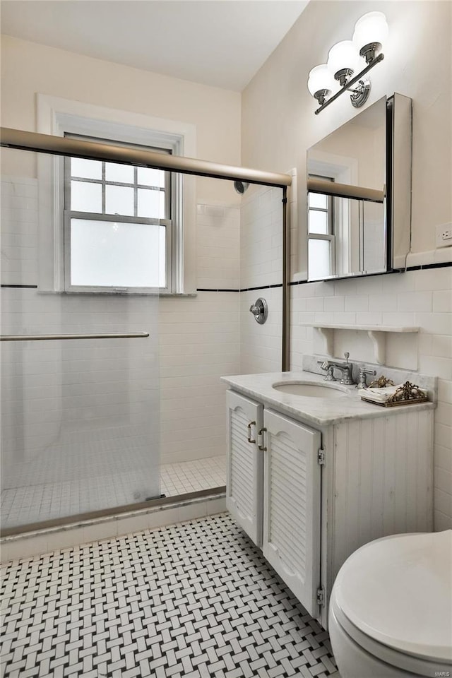 bathroom with vanity, toilet, a shower with shower door, and backsplash