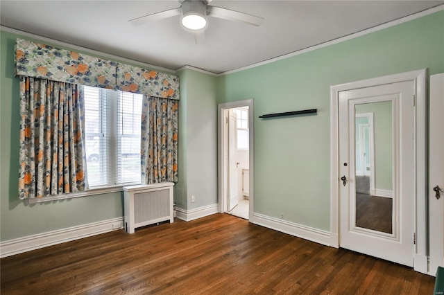 spare room with dark hardwood / wood-style flooring, radiator, ornamental molding, and ceiling fan