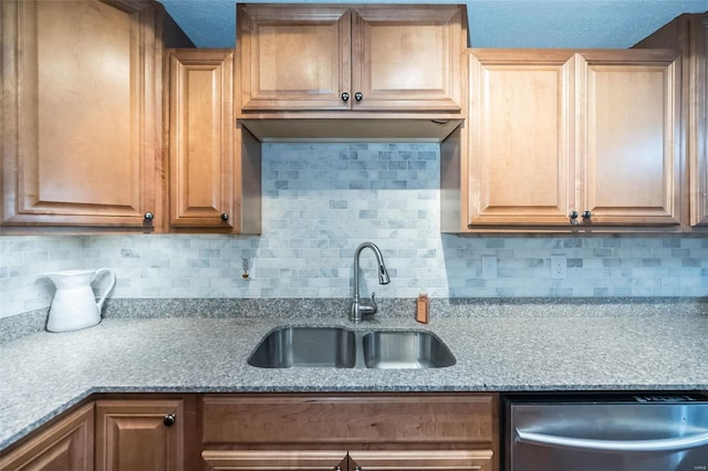 kitchen featuring light stone counters, tasteful backsplash, stainless steel dishwasher, and sink