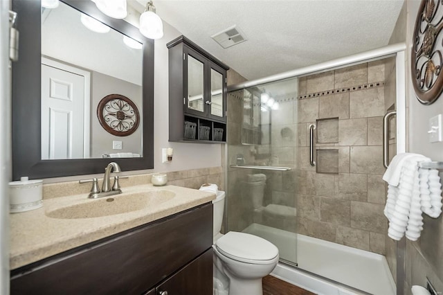 bathroom with vanity, a textured ceiling, toilet, and an enclosed shower