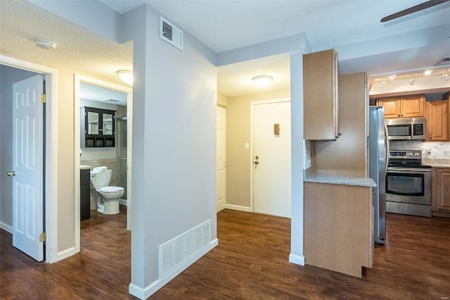 kitchen with dark hardwood / wood-style flooring, stainless steel appliances, and a textured ceiling