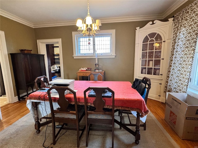 dining space featuring hardwood / wood-style flooring, an inviting chandelier, and ornamental molding