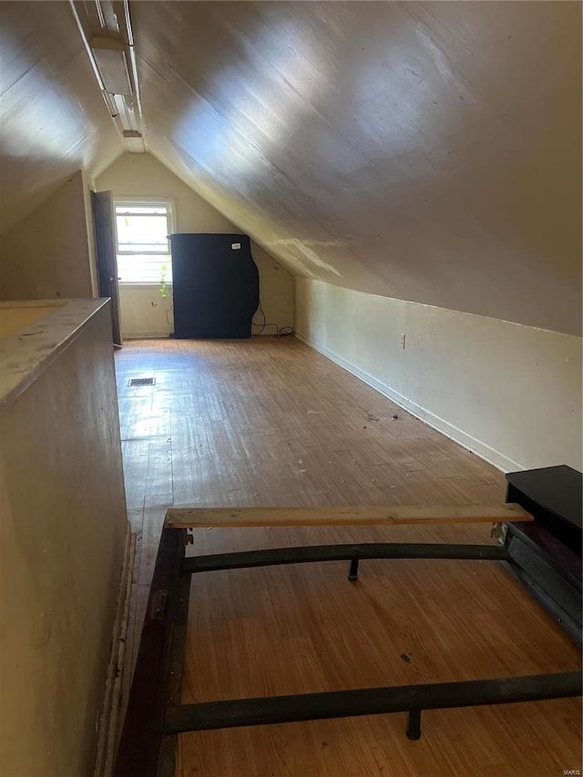 additional living space with wood-type flooring and vaulted ceiling