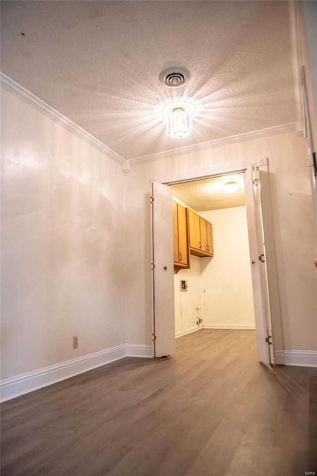 spare room featuring a textured ceiling, dark wood-type flooring, and crown molding