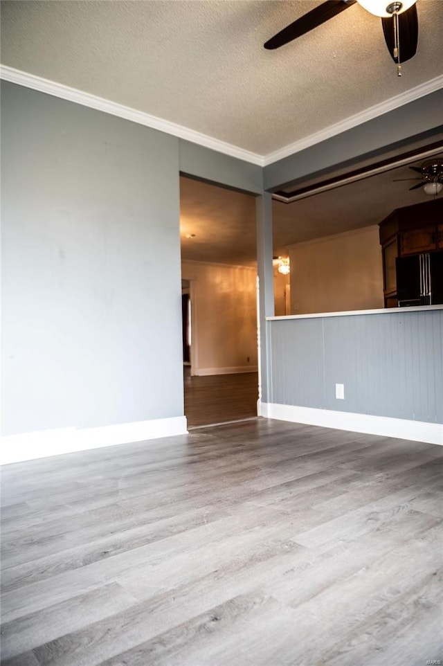 empty room with ceiling fan, hardwood / wood-style flooring, crown molding, and a textured ceiling