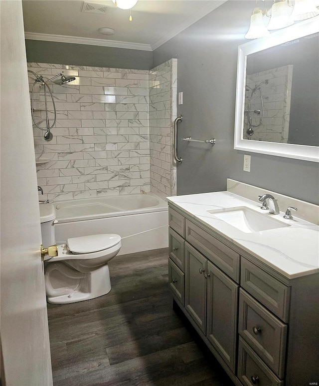 full bathroom with tiled shower / bath, vanity, ornamental molding, wood-type flooring, and toilet