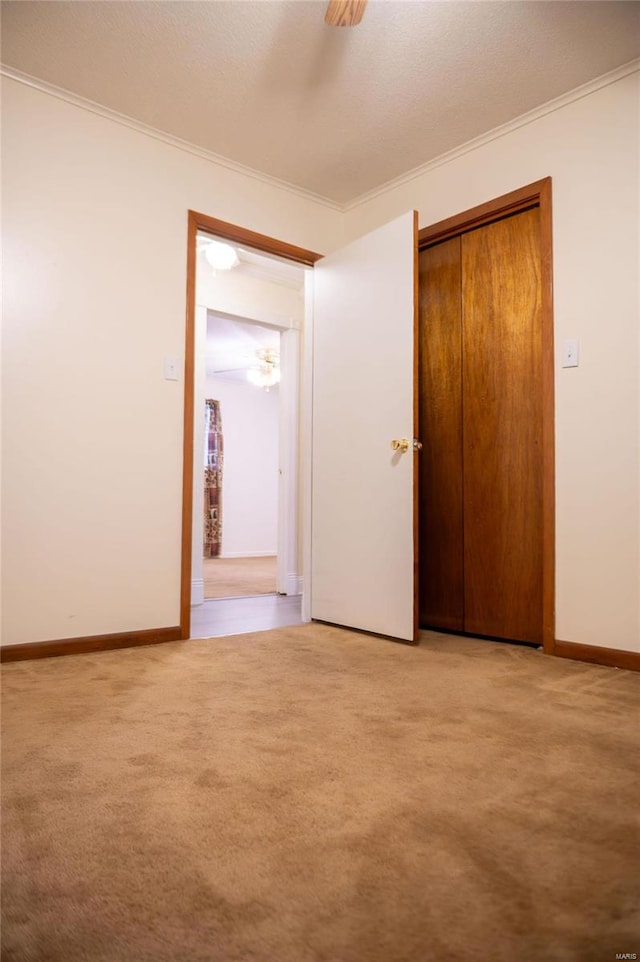 unfurnished bedroom featuring light colored carpet, a closet, and crown molding