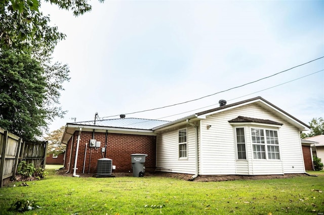 rear view of property featuring a lawn and central AC unit