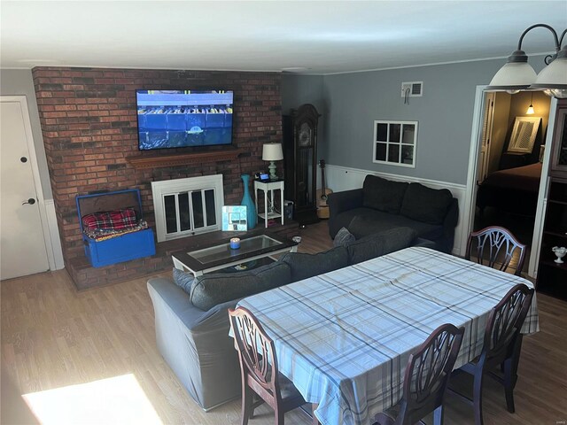 dining room with a brick fireplace and light hardwood / wood-style floors