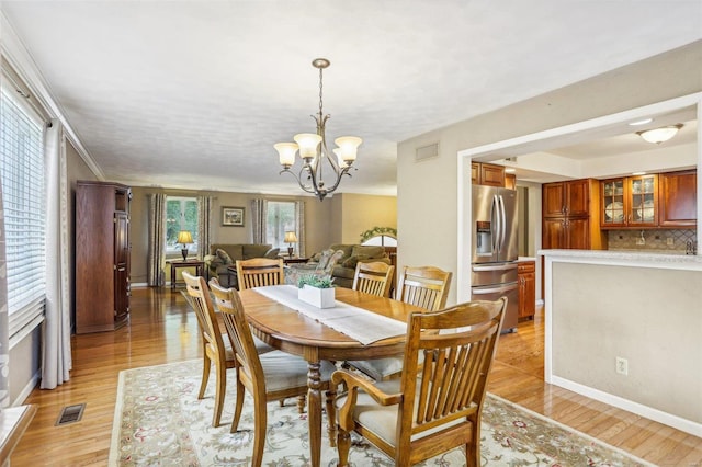 dining room with light hardwood / wood-style floors and a notable chandelier