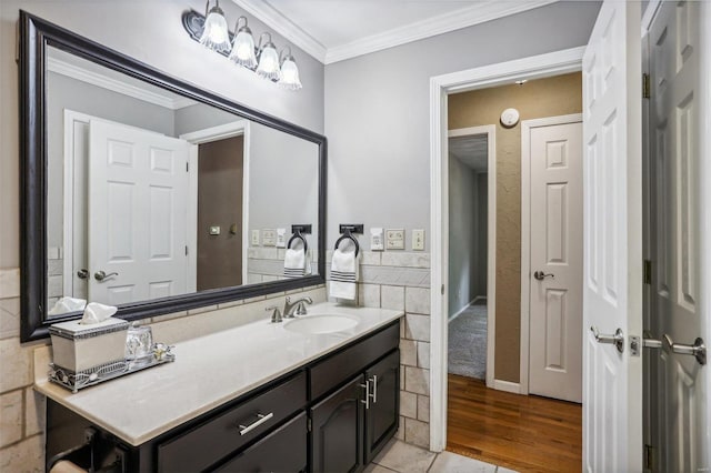 bathroom with ornamental molding, tile walls, hardwood / wood-style floors, and vanity