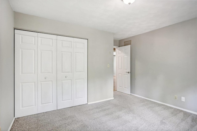 unfurnished bedroom featuring light colored carpet and a closet