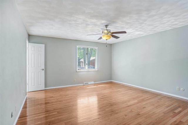 empty room with ceiling fan, a textured ceiling, and light wood-type flooring