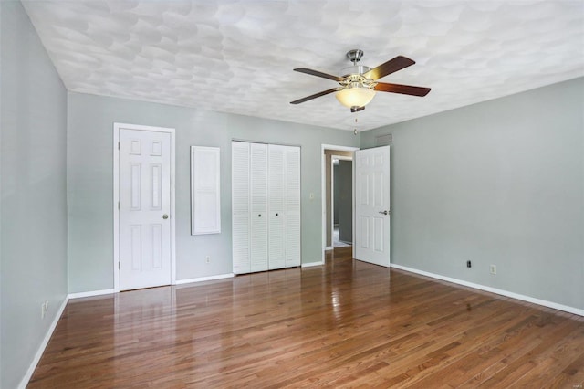 unfurnished bedroom with multiple closets, ceiling fan, and dark hardwood / wood-style floors