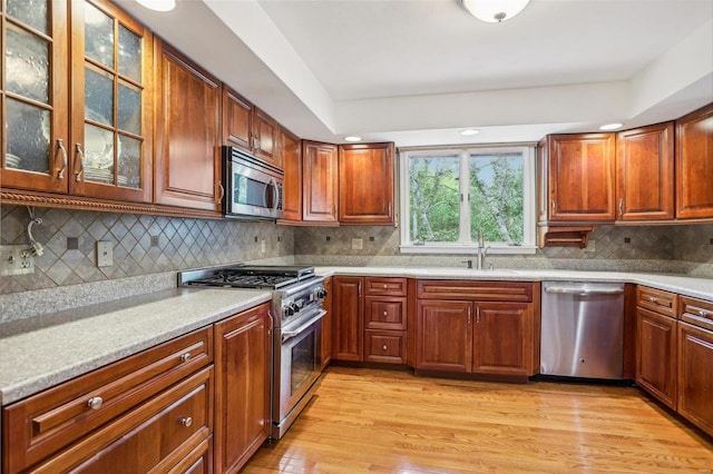 kitchen with appliances with stainless steel finishes, light hardwood / wood-style floors, and decorative backsplash