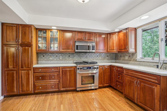 kitchen featuring light hardwood / wood-style flooring, stainless steel appliances, decorative backsplash, and sink