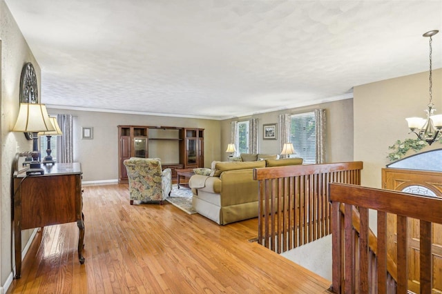 living room featuring light wood-type flooring, ornamental molding, and a notable chandelier