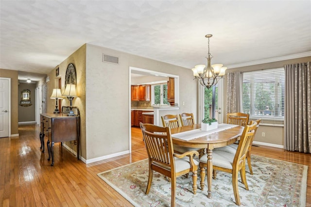 dining space with a notable chandelier, crown molding, and light hardwood / wood-style floors