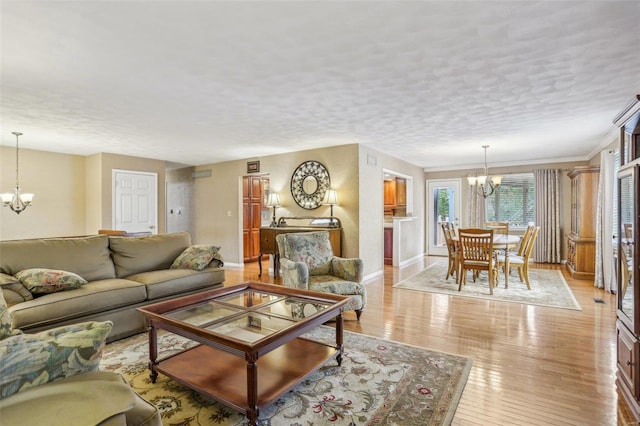 living room featuring a notable chandelier, light wood-type flooring, and a textured ceiling