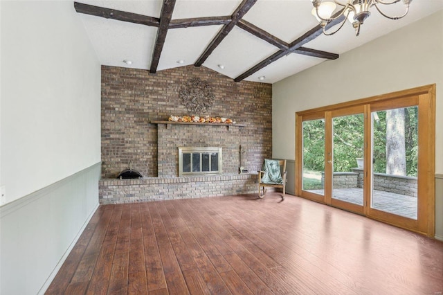 unfurnished living room with hardwood / wood-style flooring, a fireplace, an inviting chandelier, and brick wall