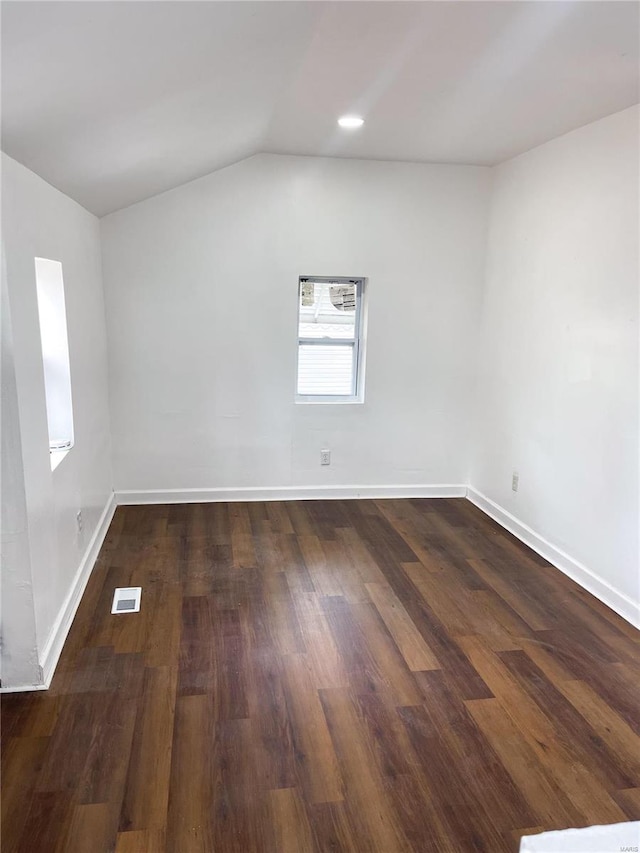 spare room with vaulted ceiling and dark hardwood / wood-style flooring