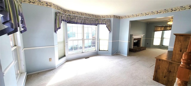 unfurnished room with ceiling fan, light colored carpet, and a brick fireplace