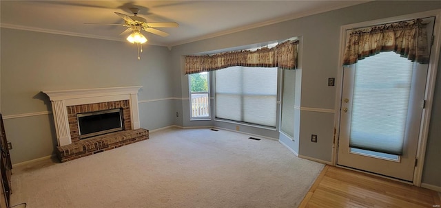 unfurnished living room with ceiling fan, a fireplace, light colored carpet, and ornamental molding