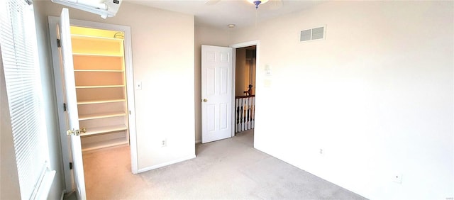 unfurnished bedroom with a walk in closet and light carpet