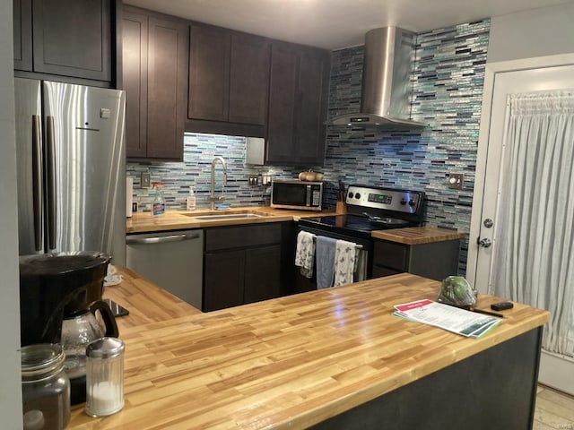 kitchen with wall chimney exhaust hood, stainless steel appliances, backsplash, wood counters, and sink