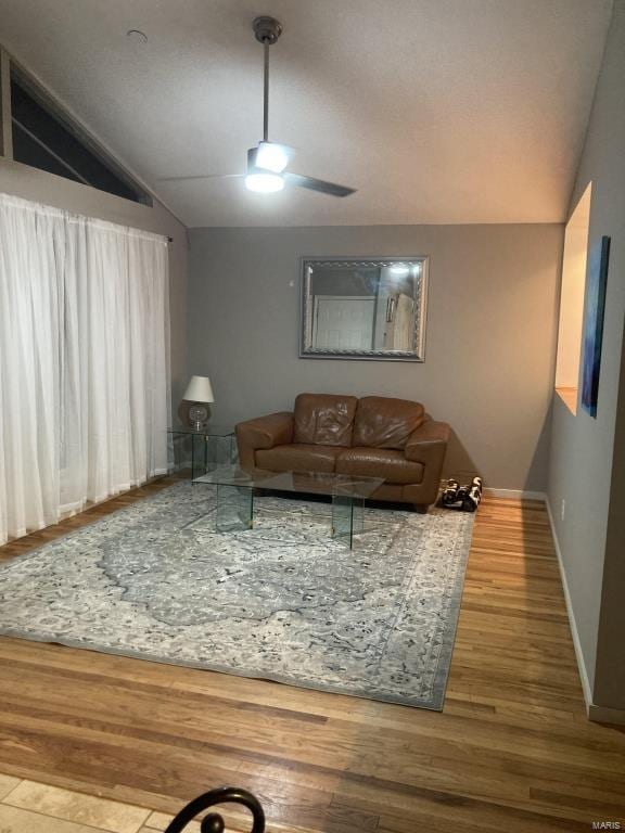 living room with lofted ceiling, hardwood / wood-style flooring, and ceiling fan