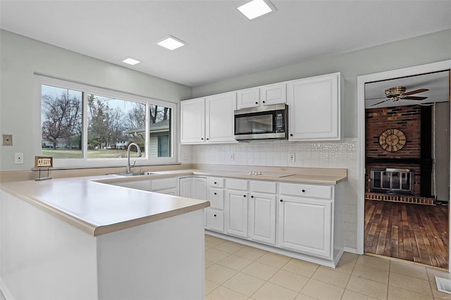 kitchen featuring sink, kitchen peninsula, light hardwood / wood-style floors, decorative backsplash, and white cabinets