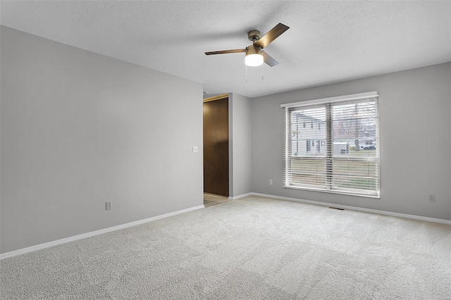 spare room featuring a textured ceiling, ceiling fan, and light carpet