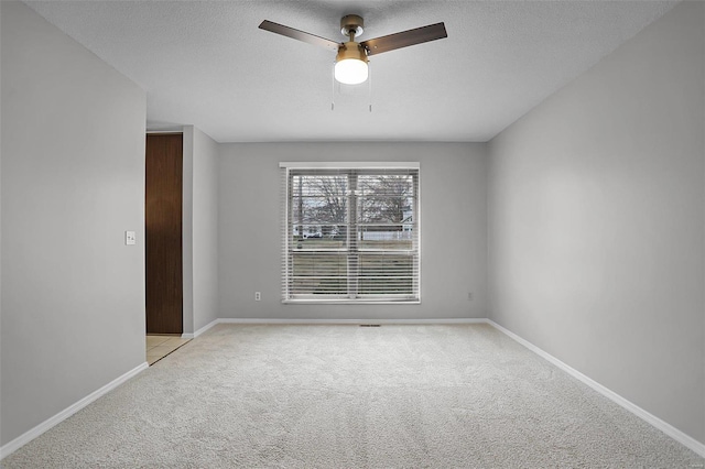 spare room with ceiling fan, light colored carpet, and a textured ceiling