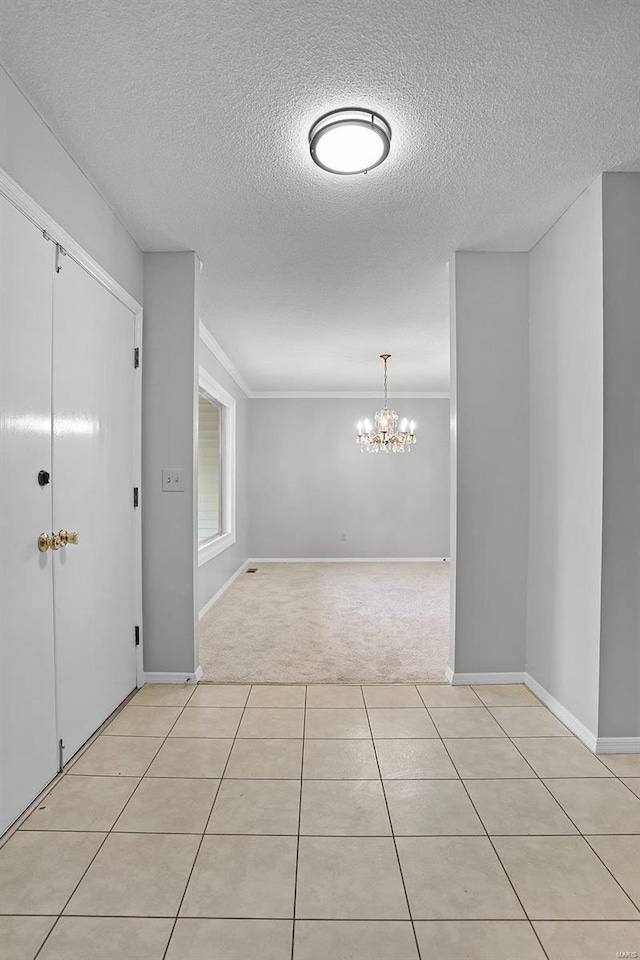 carpeted foyer with a chandelier, a textured ceiling, and ornamental molding