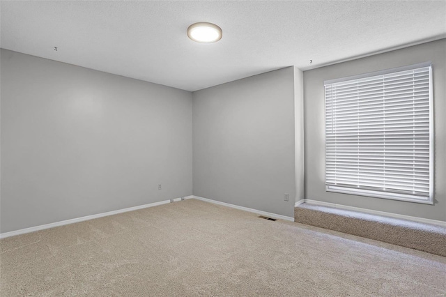 carpeted spare room with a textured ceiling