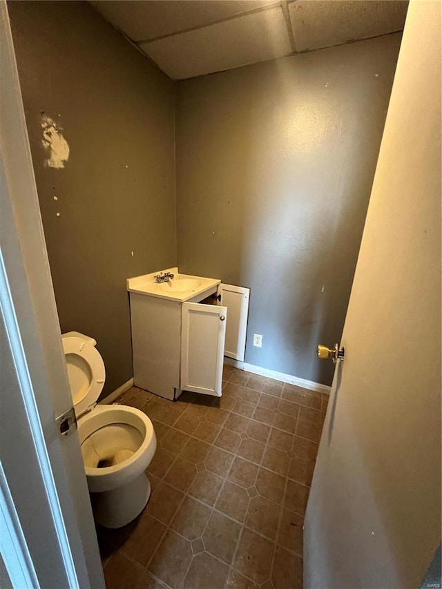 bathroom featuring tile patterned flooring, vanity, toilet, and a drop ceiling