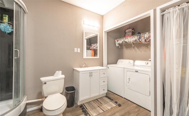 bathroom with vanity, washing machine and clothes dryer, curtained shower, hardwood / wood-style flooring, and toilet