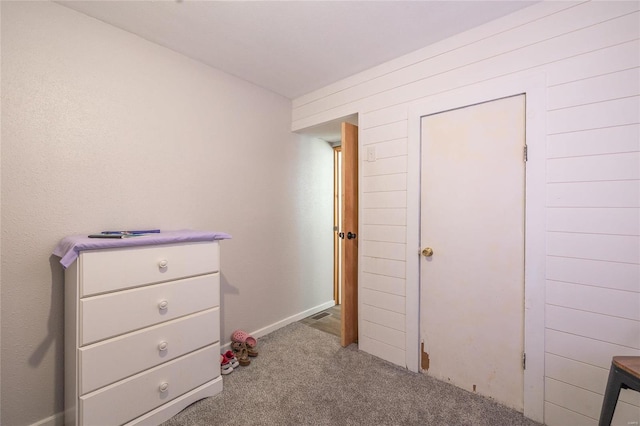 unfurnished bedroom with light carpet and wood walls