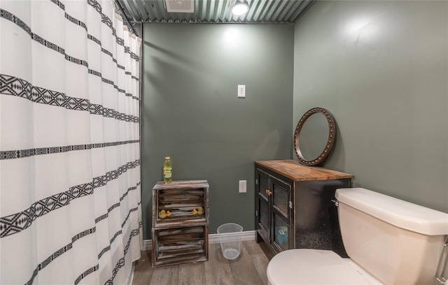 bathroom featuring a shower with shower curtain, hardwood / wood-style flooring, and toilet