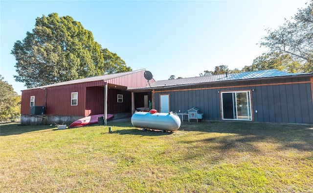 rear view of house with central AC unit and a yard