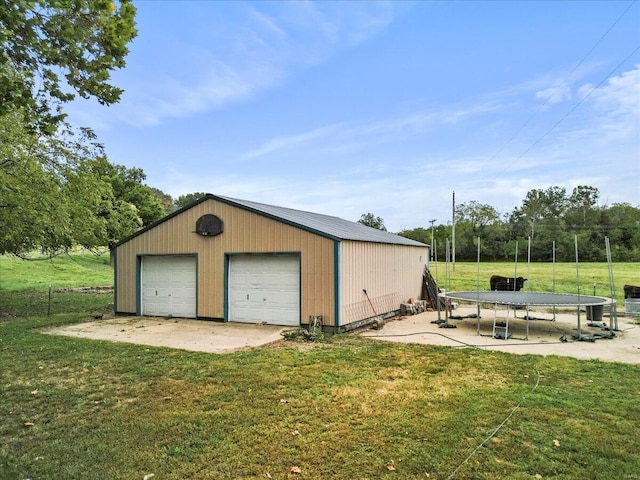 garage with a trampoline and a lawn