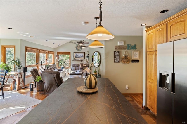 dining area featuring ceiling fan, vaulted ceiling, a fireplace, and dark hardwood / wood-style flooring