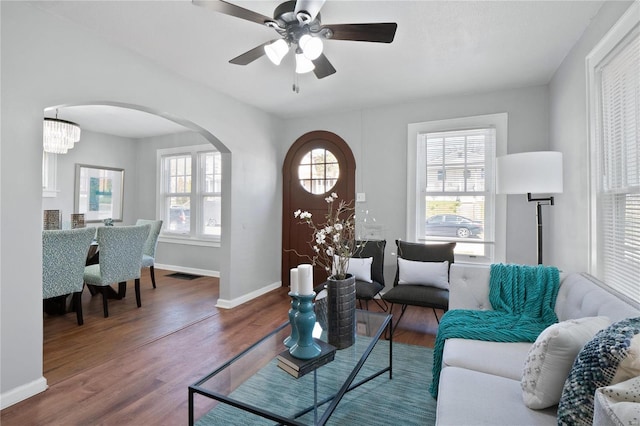 living room featuring wood-type flooring, ceiling fan with notable chandelier, and a wealth of natural light